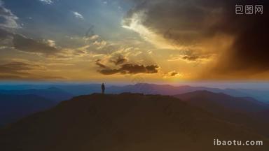 无人机拍摄黄昏时男人站在山顶上
